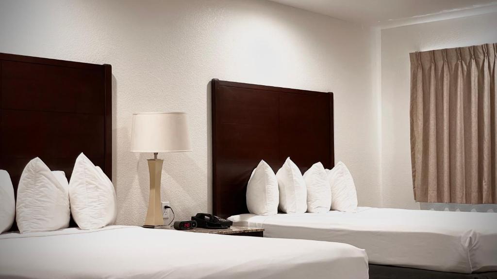 duas camas com almofadas brancas num quarto de hotel em The Yosemite Inn em Mariposa