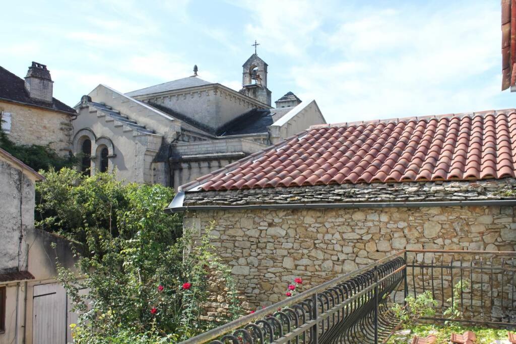 a stone building with a church in the background at Escapade en Périgord in Villefranche-du-Périgord