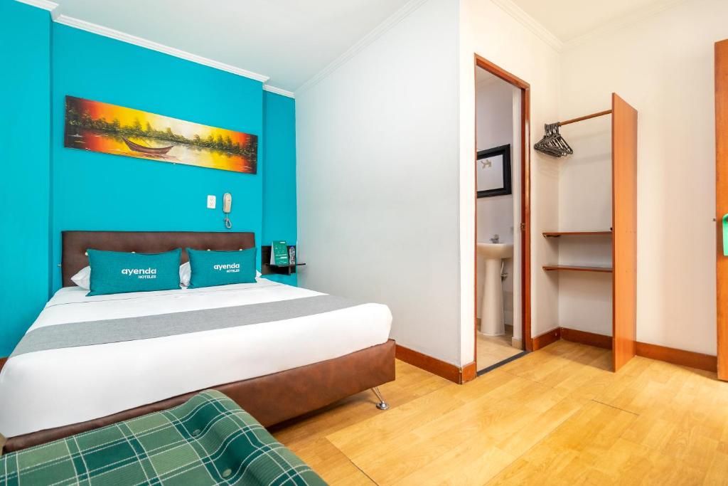 a bedroom with a large bed and a blue wall at Ayenda Palermo Plaza in Bogotá