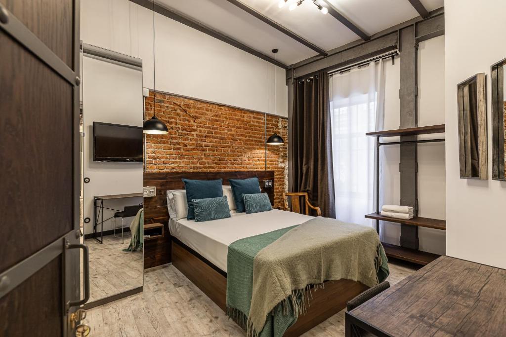 sypialnia z łóżkiem i ścianą z cegły w obiekcie Waou Boutique SOL w Madrycie