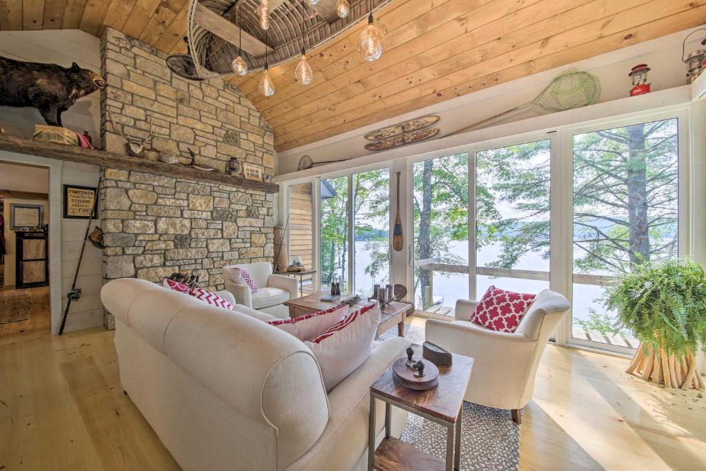 a living room with couches and a stone wall at Beautiful Embden Pond Cabin with Dock and Kayaks! in Embden