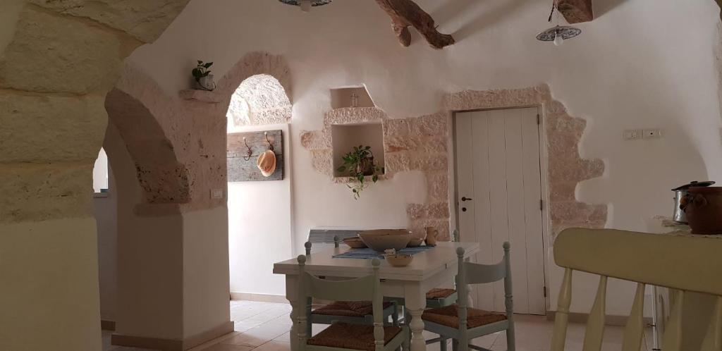 une cuisine avec une table et une table ainsi qu'une chambre avec une porte dans l'établissement Trullo Il cantagallo, à Locorotondo
