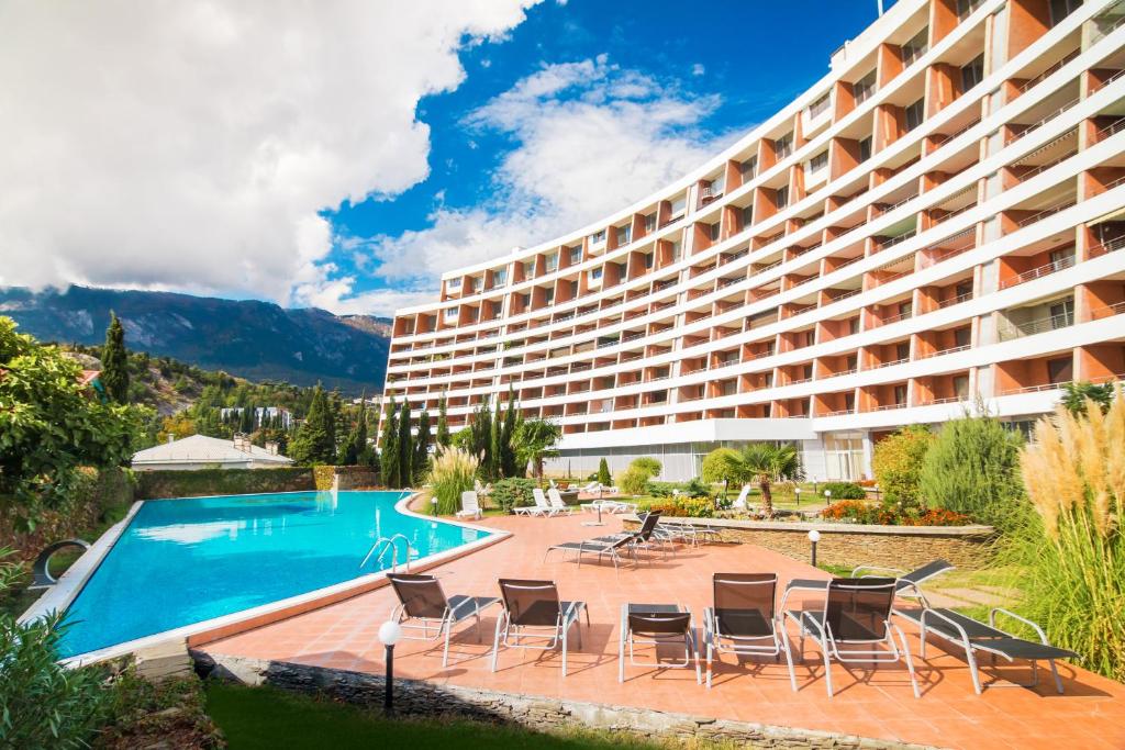 a hotel with a swimming pool and lounge chairs at Familiya Apartments in Gurzuf