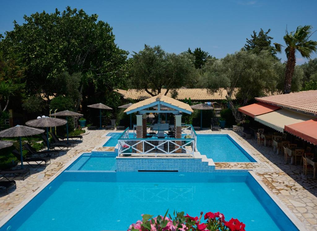 a pool at a resort with tables and umbrellas at Villaggio Maistro in Lefkada Town