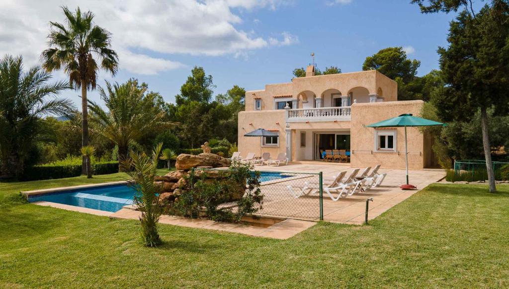 uma casa com piscina em frente a um quintal em Villa Coqueta em Sant Josep de sa Talaia