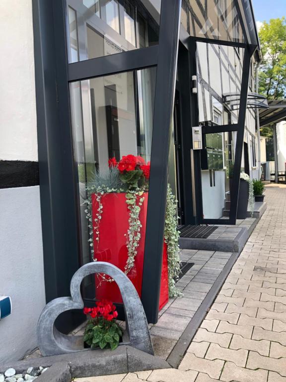 a bench in front of a building with red flowers at Ferienwohnungen Margot in Iserlohn