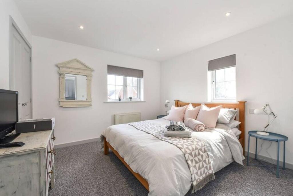 a bedroom with a large bed and a television at The Little House, boutique home near the sea in Chichester
