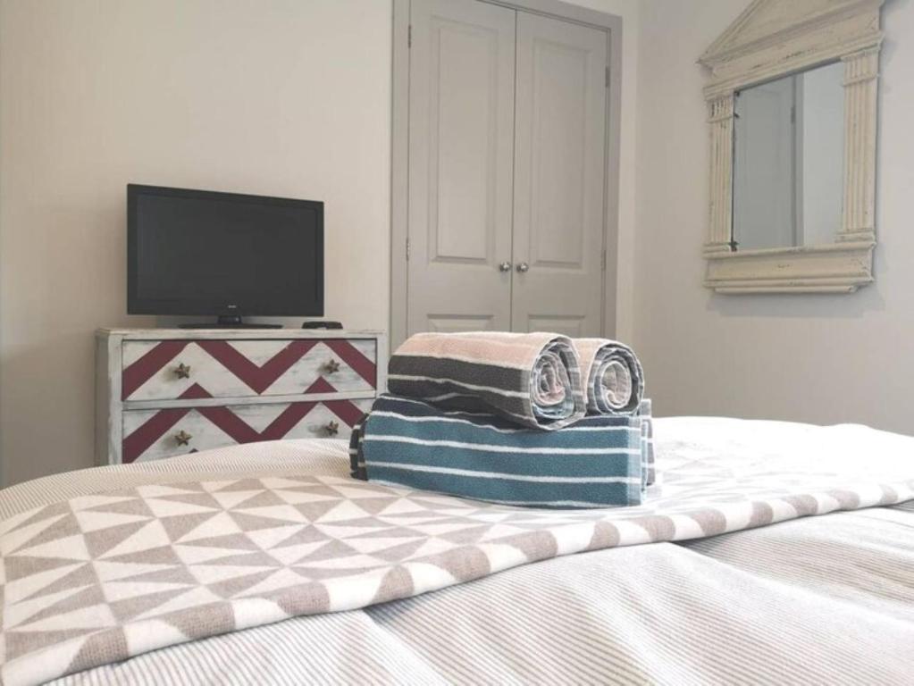 a bedroom with a bed with two towels on it at The Little House, boutique home near the sea in Chichester