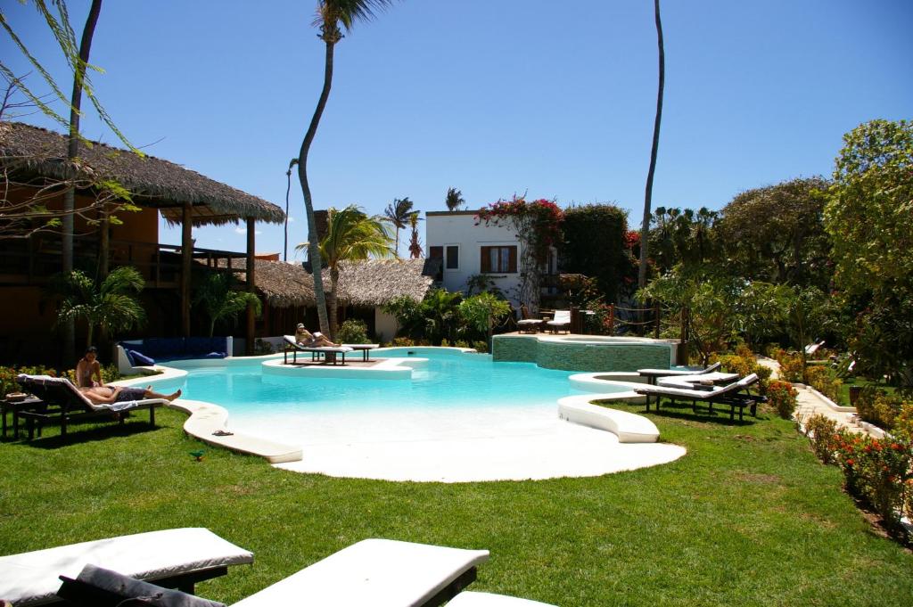 a swimming pool with people sitting in chairs in a yard at My Blue Hotel in Jericoacoara