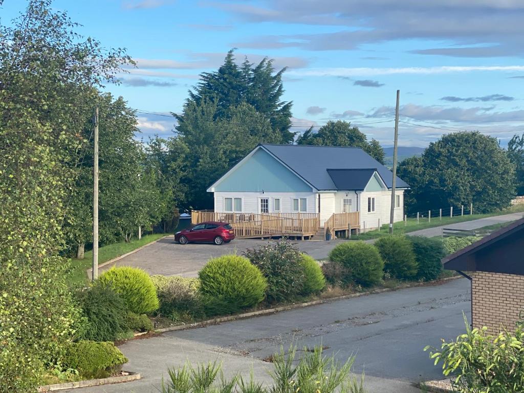 una casa con un coche rojo aparcado en una entrada en Linne Lodge, en Tain