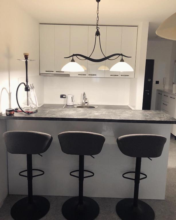 a kitchen with a counter with two bar stools at Centrum in Subotica