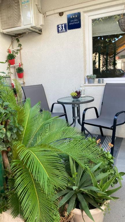 um pátio com duas cadeiras, uma mesa e plantas em Apartment Ria em Split