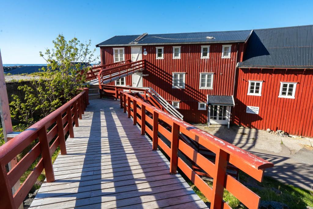 eine Holzbrücke, die zu einem roten Gebäude führt in der Unterkunft Lofoten Å HI hostel in Å