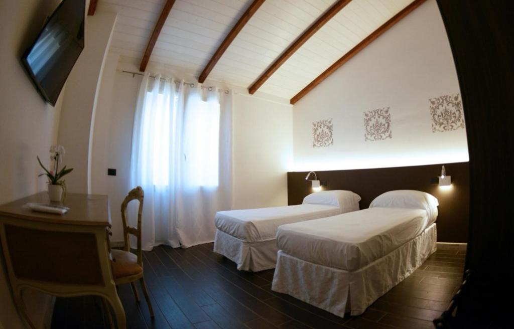 a bedroom with two beds and a table and a window at B&B Riva del Gallo in Tresigallo