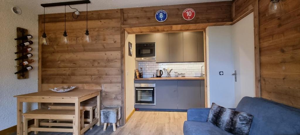 a living room with a blue couch and a kitchen at Luxury Central Apartment MONTCHAVIN in Bellentre