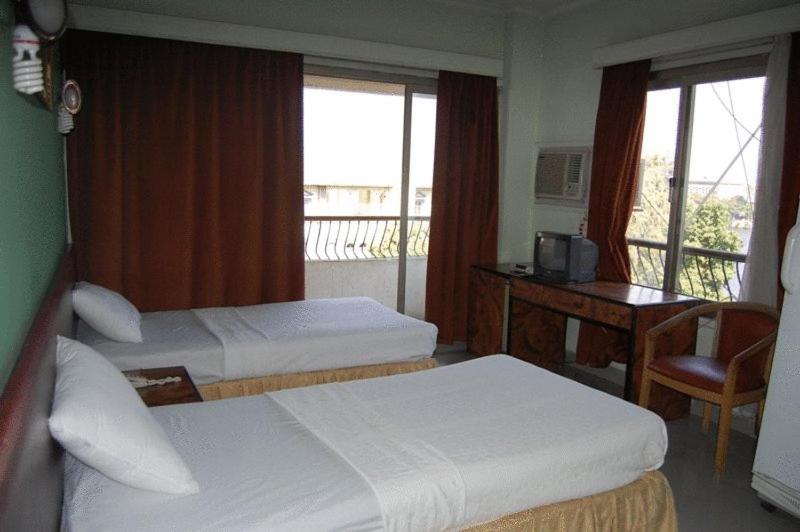 a hotel room with two beds and a desk at Nile Zamalek Hotel in Cairo