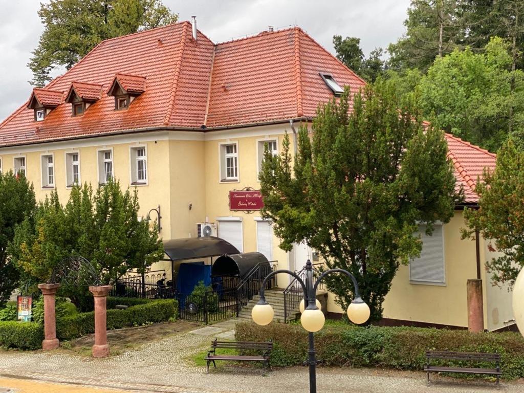 a house with a red roof and a table and benches at Zielone walizki in Polanica-Zdrój