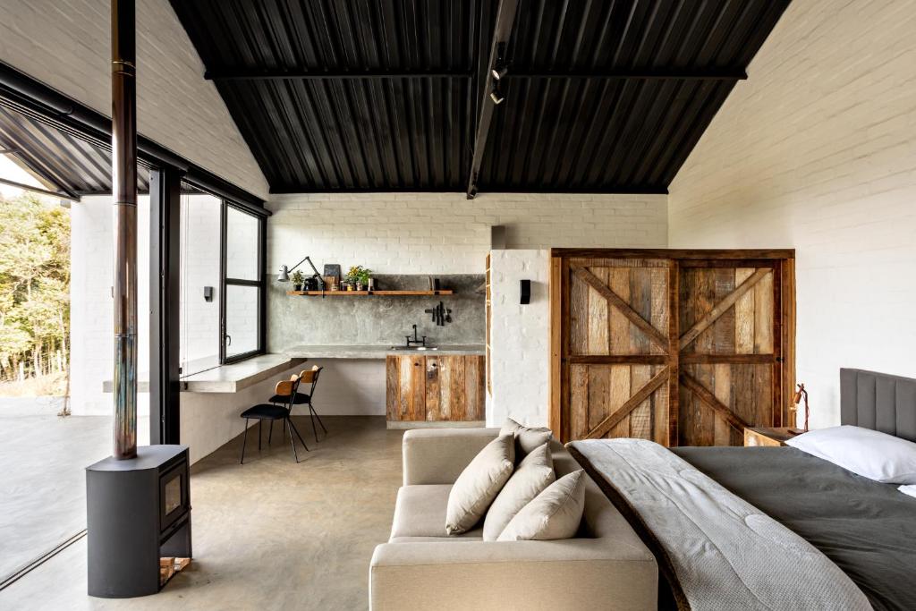 1 dormitorio con 1 cama y 1 sofá en una habitación en Mataka'a - Chalé Industrial na Mantiqueira, en Gonçalves