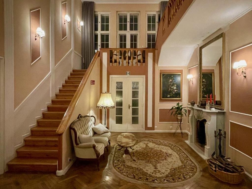 a living room with a staircase with a chair and a table at Villa ANSER in Połczyn-Zdrój