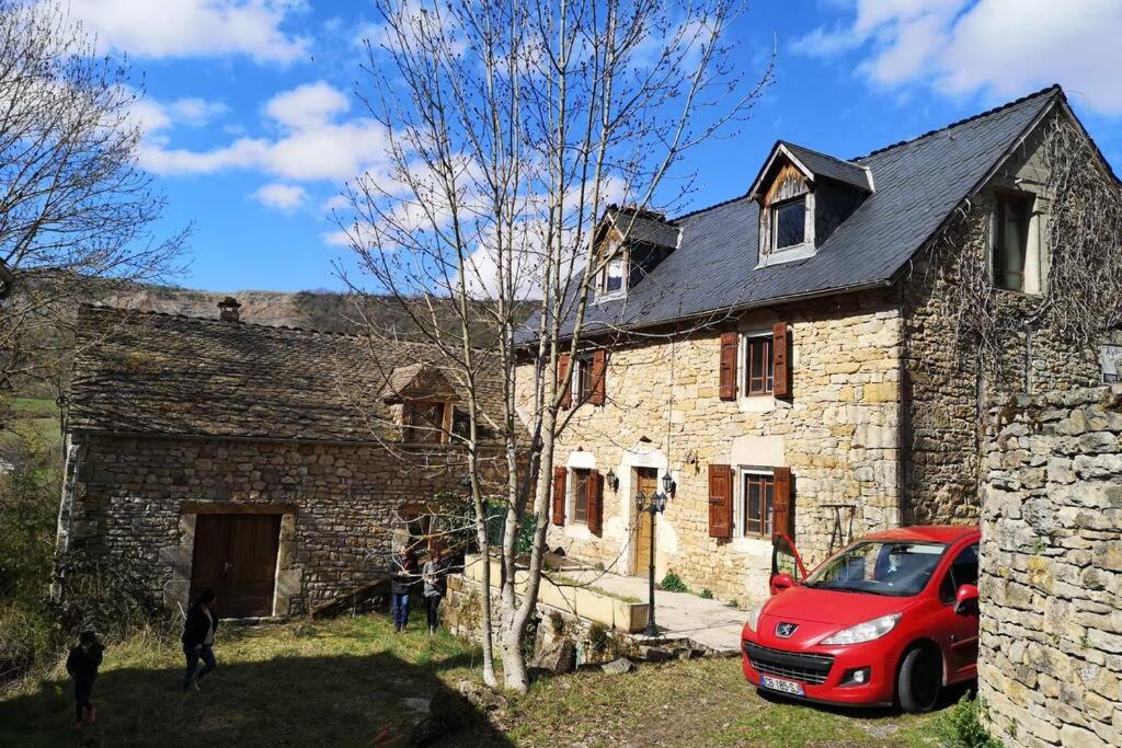 un coche rojo estacionado frente a una casa de piedra en Maison traditionnelle en Lozère, en Saint-Saturnin-de-Tartaronne