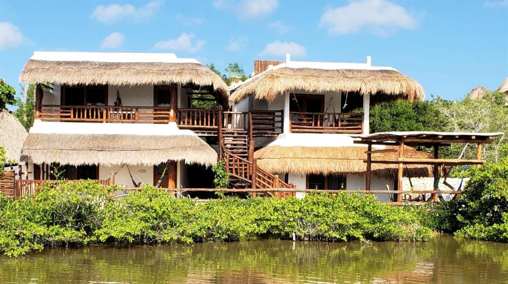 un complejo con dos cabañas junto a un cuerpo de agua en La Casa del Alux - Adults Only, en Isla Holbox