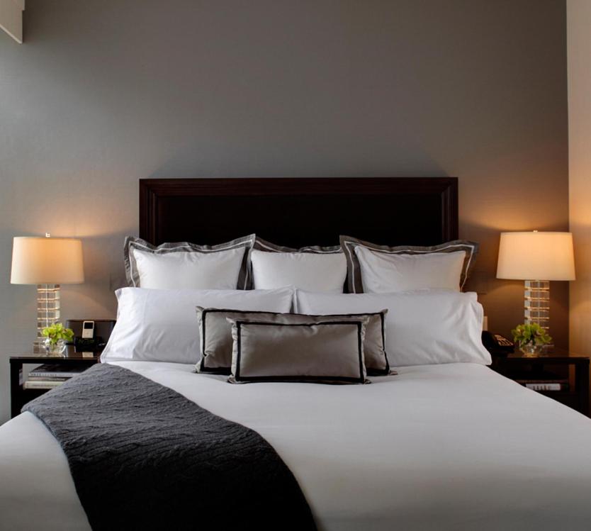 a large bed with white pillows and two lamps at Trump International New York in New York