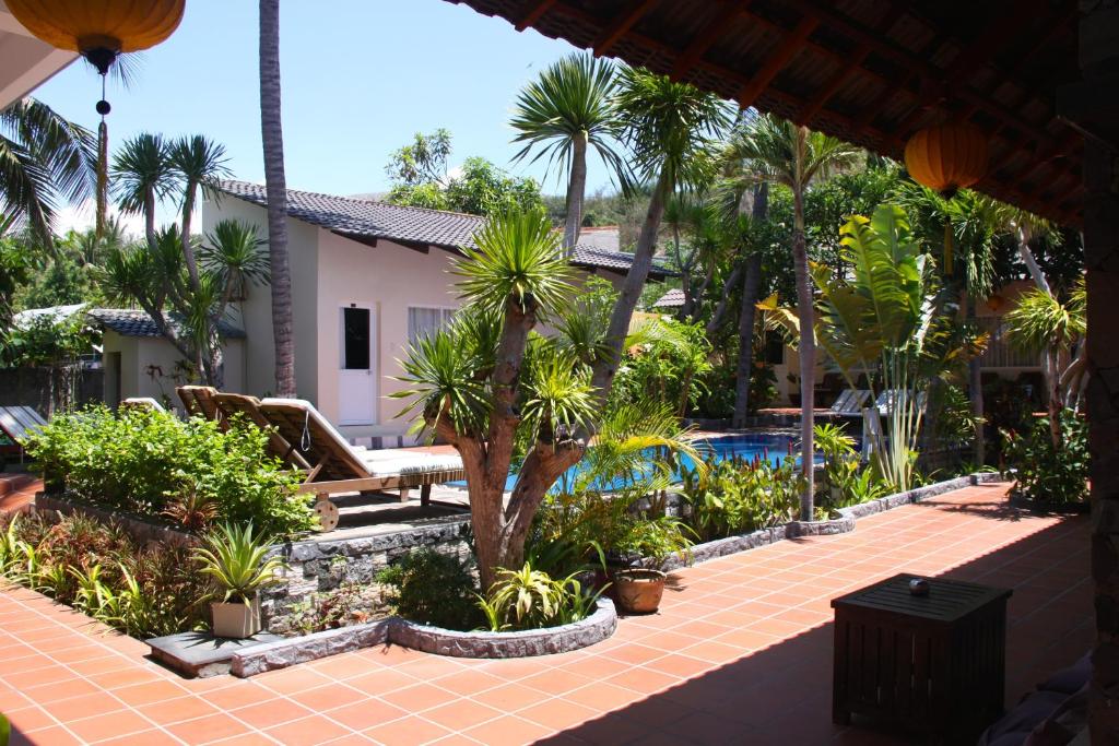 un patio con palmeras y una piscina en Xin Chao Hotel, en Mui Ne