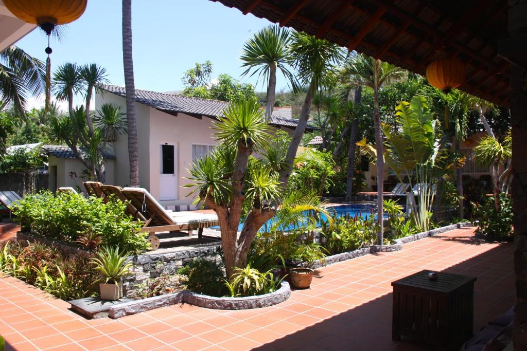 a courtyard with palm trees and a swimming pool at Xin Chao Hotel in Mui Ne