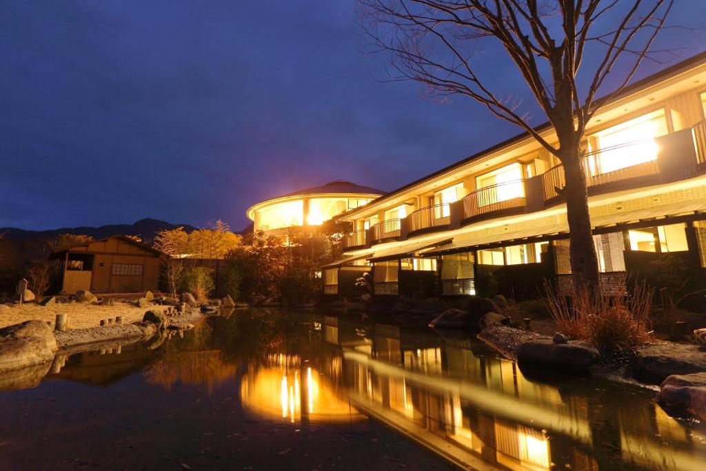 un edificio con un río delante de él por la noche en Hotel Yumeshizuku, en Minami Aso