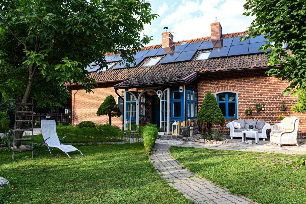 ein Backsteinhaus mit Solardach und Stühlen im Hof in der Unterkunft Wilaneska Prośno in Prośno