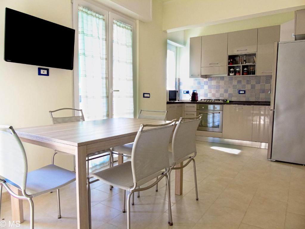 eine Küche mit einem Tisch und Stühlen sowie einem Kühlschrank in der Unterkunft Pietra Home, posto auto, AC ,WIFI, 150mt dal mare in Pietra Ligure