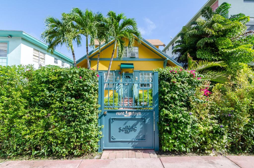a blue gate in front of a house with bushes at Sunflower Boutique Hotel Apartments in Miami Beach