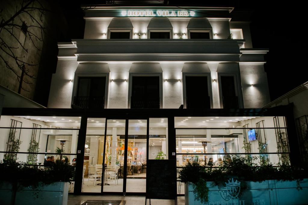 un edificio bianco con un negozio di fronte alla notte di Hotel Boutique Vila 135 a Tirana