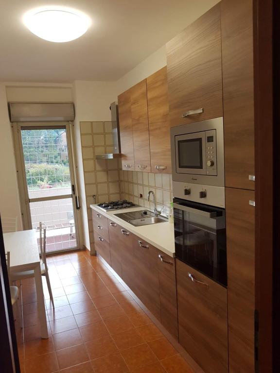 a kitchen with wooden cabinets and a microwave and a table at Casa Stazione Magliana in Rome