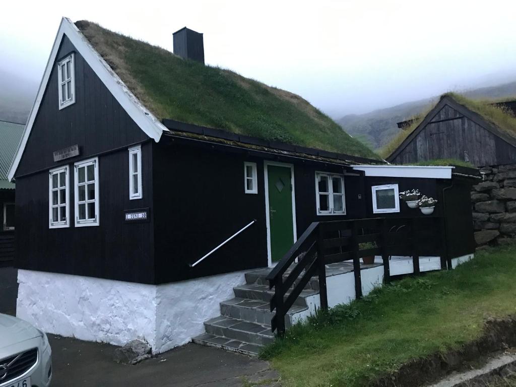 a black and white house with a grass roof at holiday cottage in Tjørnuvík in Tjørnuvík