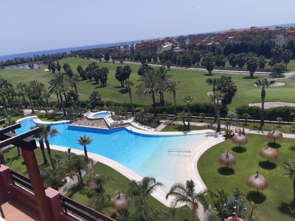 - une vue aérienne sur la piscine du complexe bordée de palmiers dans l'établissement Apartamento exclusivo playa granada golf, à Motril