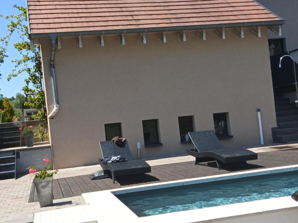 eine Terrasse mit 2 Stühlen und einem Pool in der Unterkunft Repos et convivialité, wellness, spa, sauna, piscine in Schorbach