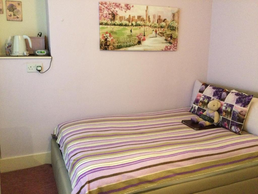 a bedroom with a bed with a painting on the wall at Arun Sands Rooms in Littlehampton