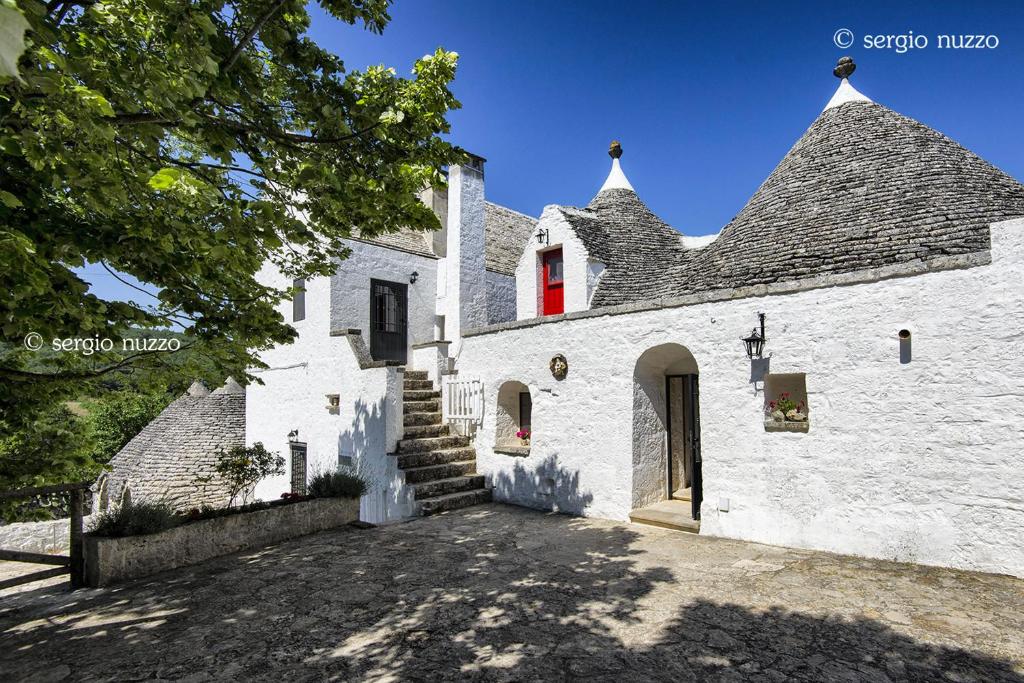 a white building with a red window and stairs at Masseria Mazzalorsa in Alberobello