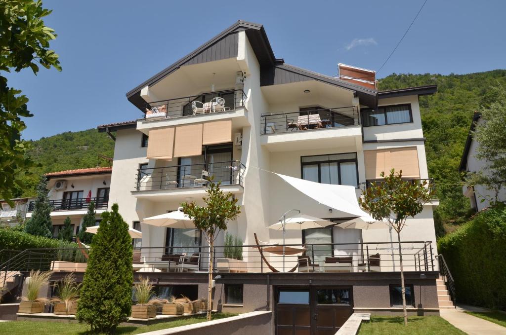 un grand bâtiment blanc avec des parasols en face de celui-ci dans l'établissement Villa Katerina, à Ohrid