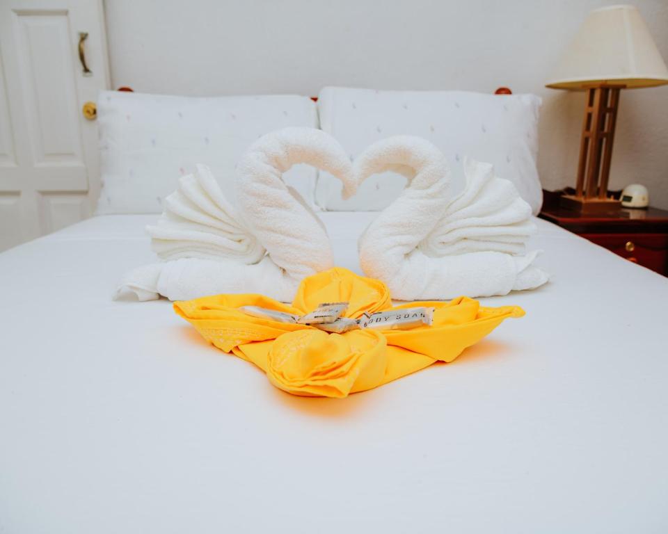 dois cisnes feitos de toalhas numa cama em Wanigi Guesthouse em Punta Gorda
