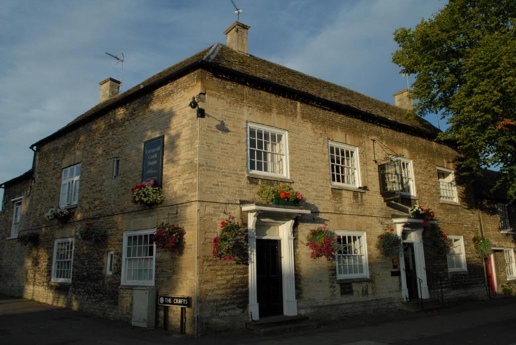 un antiguo edificio de ladrillo con flores en las ventanas en Corncroft Guest House, en Witney