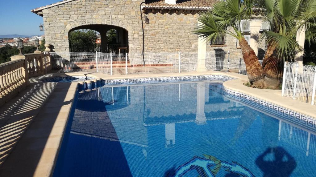 ein großer Pool mit einer Palme neben einem Gebäude in der Unterkunft Spacious villa with large private pool and incredible views in Luchente
