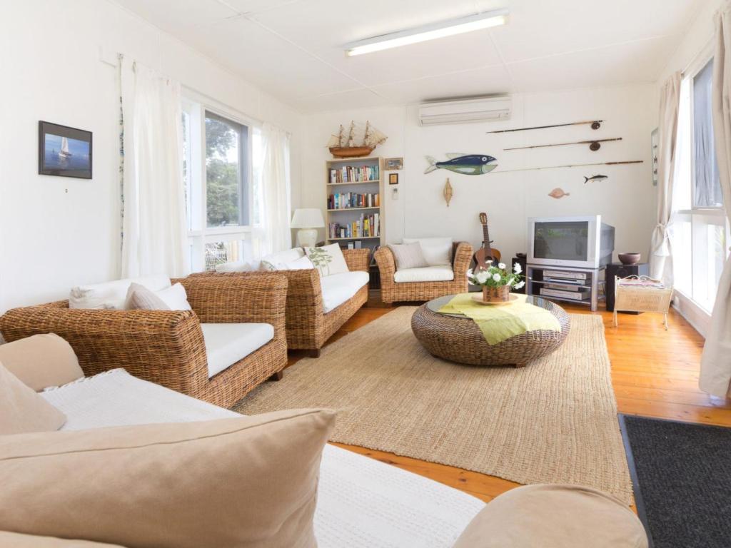 a living room with wicker furniture and a tv at Home Sweet Home Mount Martha in Mount Martha