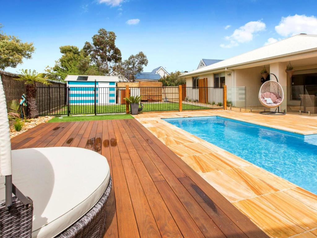 a backyard with a swimming pool and a wooden deck at Malibu Safety Beach in Safety Beach