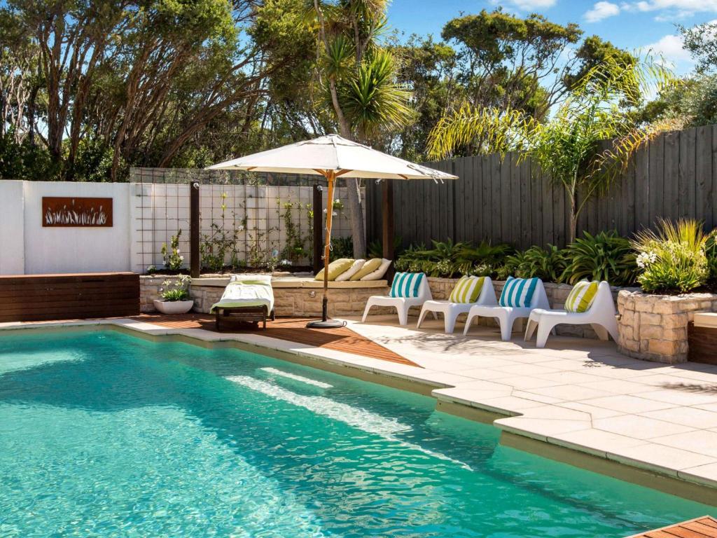 een zwembad met ligstoelen en een parasol bij WAIKIKI BLAIRGOWRIE in Blairgowrie