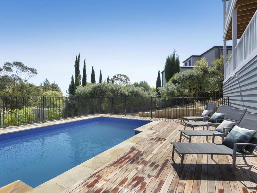 a swimming pool with lounge chairs on a wooden deck at Windspray Mount Martha in Mount Martha