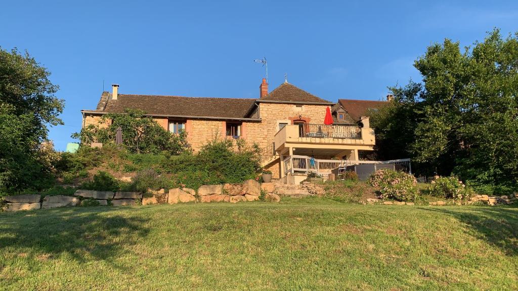 a large brick house with a balcony on a yard at La Maison de la Colline in Vers