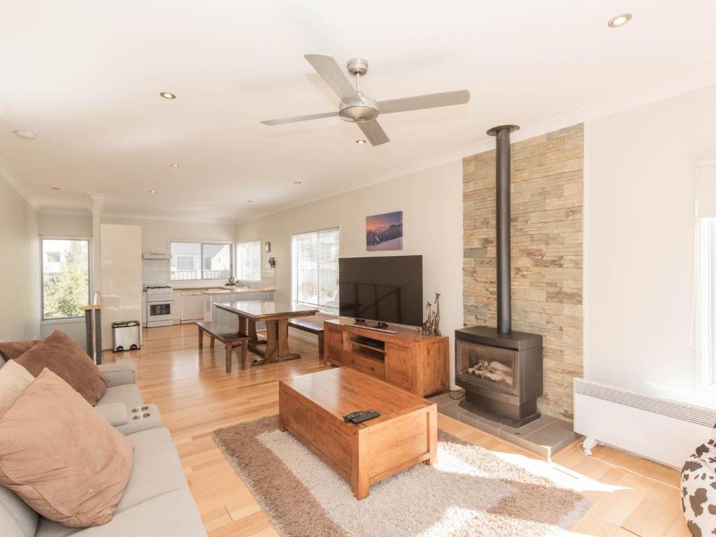 a living room with a couch and a fireplace at Aspect 1 8a Poley Cow Lane in Jindabyne