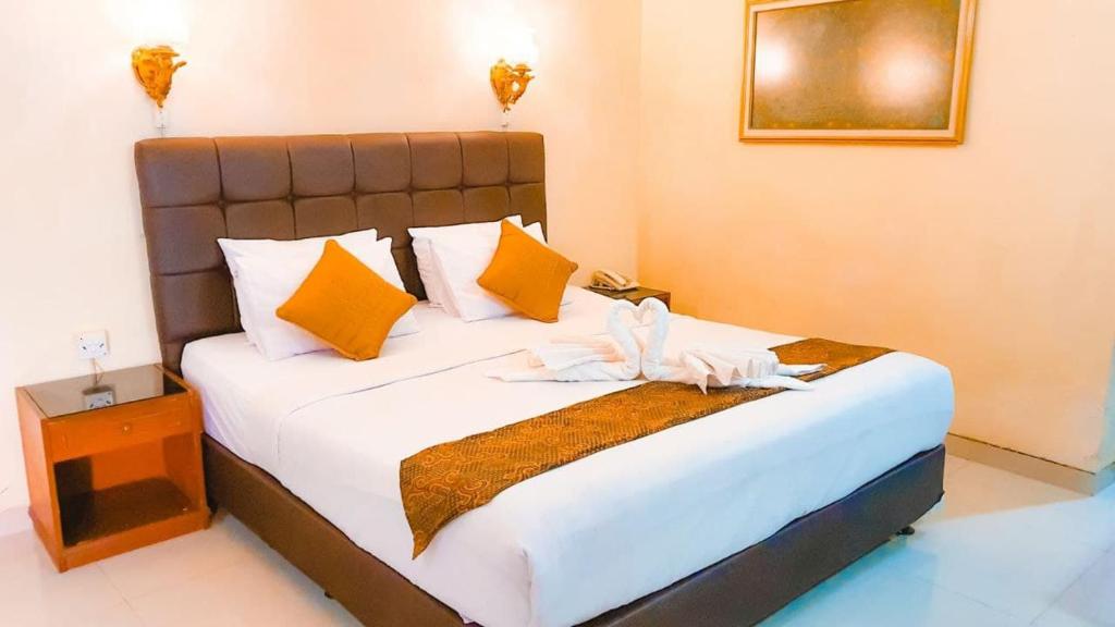 1 dormitorio con 1 cama grande con almohadas amarillas y naranjas en Mandala Wisata Hotel, en Solo